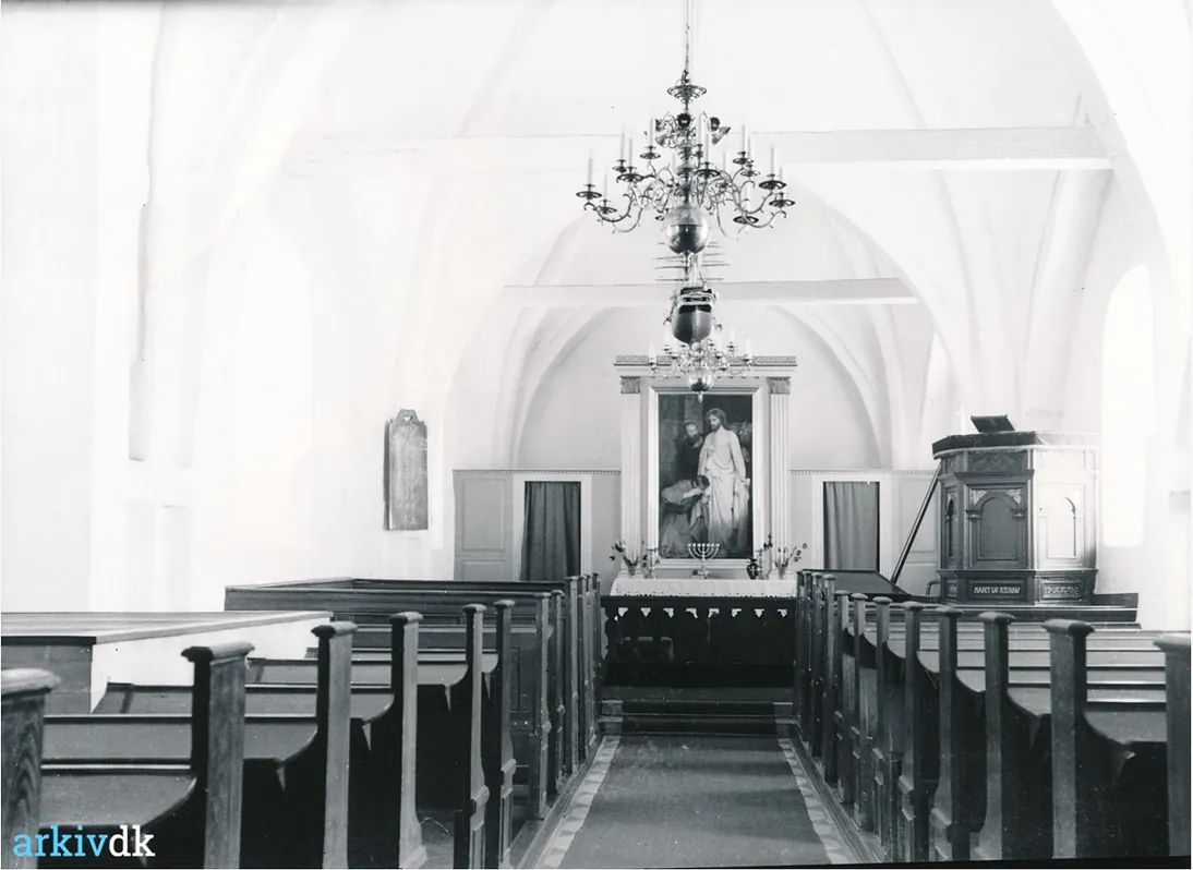 Lyst interiør med bænk og alter.